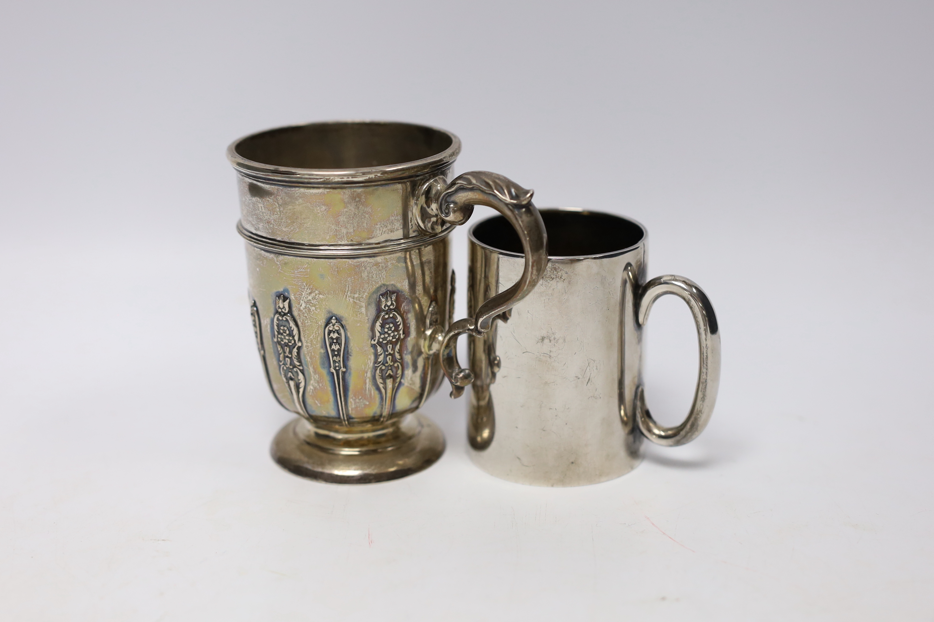 A George V silver christening mug, with card cut decoration, Sibray, Hall & Co, Sheffield, 1922, height 10.1cm and one other smaller George V silver christening mug, 8.7oz.